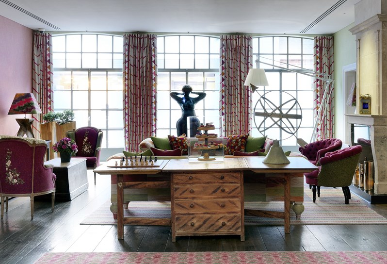 A colourful drawing room with a sculpture of Aphrodite in front of large Crittall style windows