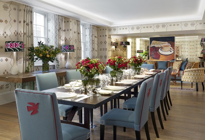 Rocklin room set for a formal dinner with red roses in vases. The room has cream printed wallpaper.