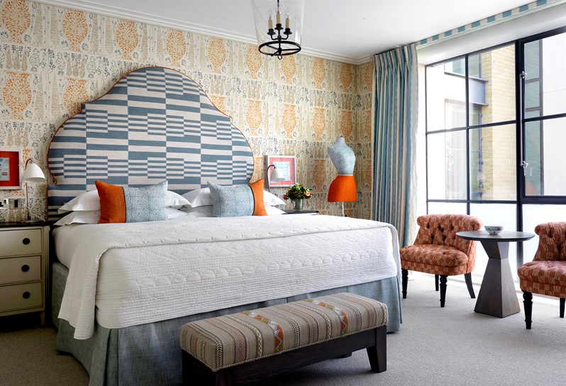 a large bedroom with blue and orange walls, a striped headboard above a double bed
