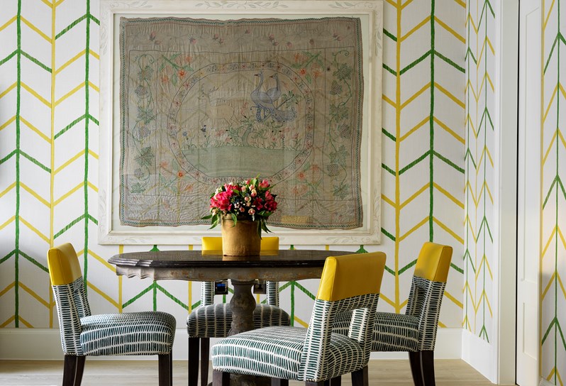 A vibrant suite with yellow and green striped walls and a round table surrounded by yellow chairs