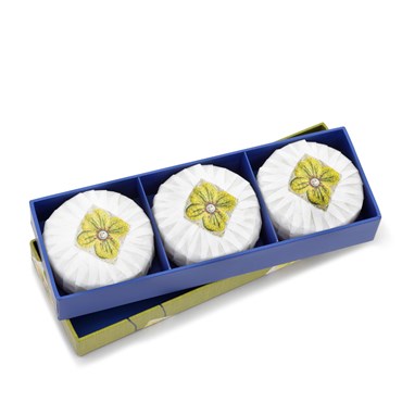 A box of three round soaps scented in gardenia sandalwood and wrapped in white paper. They are presented in an elongated box with a green friendly flowers design applied.