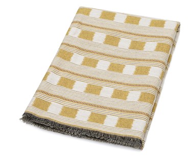Kit Kemp for Christopher Farr. A folded Lost and Found throw with design featuring yellow and cream lines interrupted by alternating boxes and dotted red and white lines.