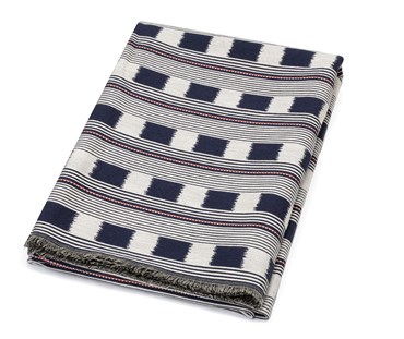 Kit Kemp for Christopher Farr. A folded Lost and Found throw with design featuring dark navy blue and cream lines interrupted by alternating boxes and dotted red and white lines. Showing both sides of the fabric and frayed edges.