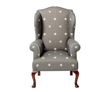 Front facing Kit's Wing Armchair, upholstered in Kit Kemp for Andrew Martin 'Over the Moon' fabric in Charcoal Grey, with off white leather piping; wooden legs in dark Mahogany finish, with chrome studding at the top of the leg