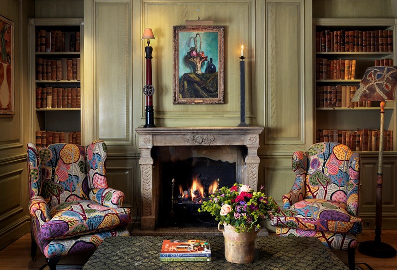 A fireplace surrounded by two colourful armchairs