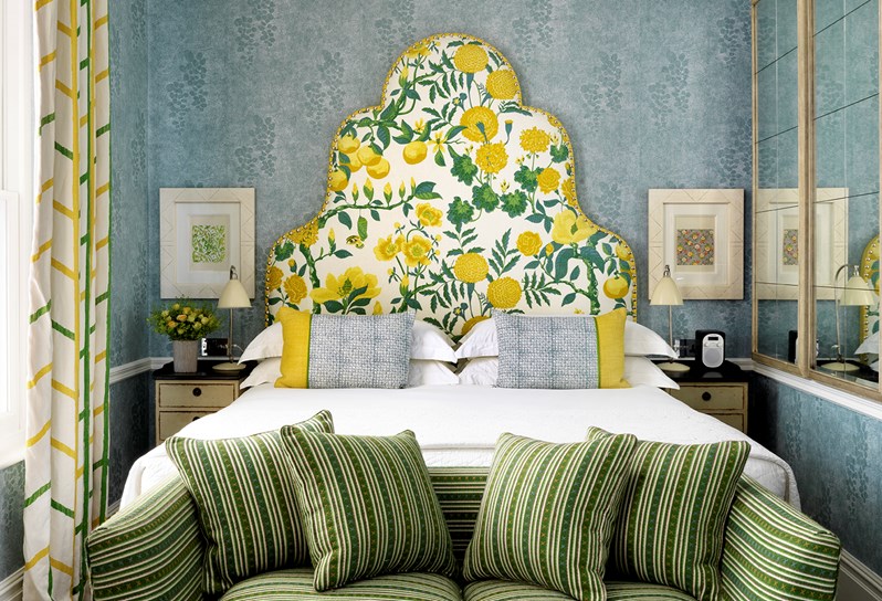 Lemon headboard and blue patterned wallpaper with king size bed