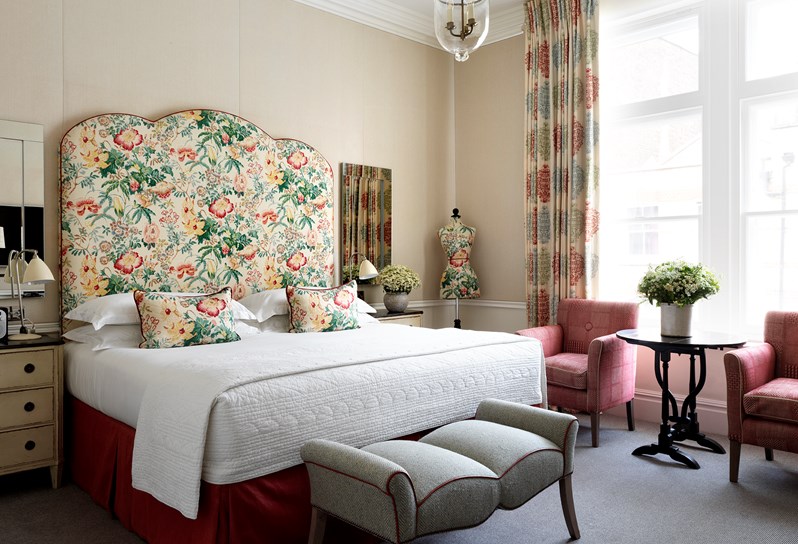 A luxury bedroom with cream walls and a large bed with a floral headboard