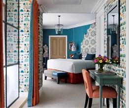 Looking through a hallway into a bedroom with bright turquoise walls and a king size bed with a statement headboard