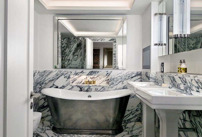 A luxurious bathroom with white arabestcato marble on the walls and a free standing bathtub