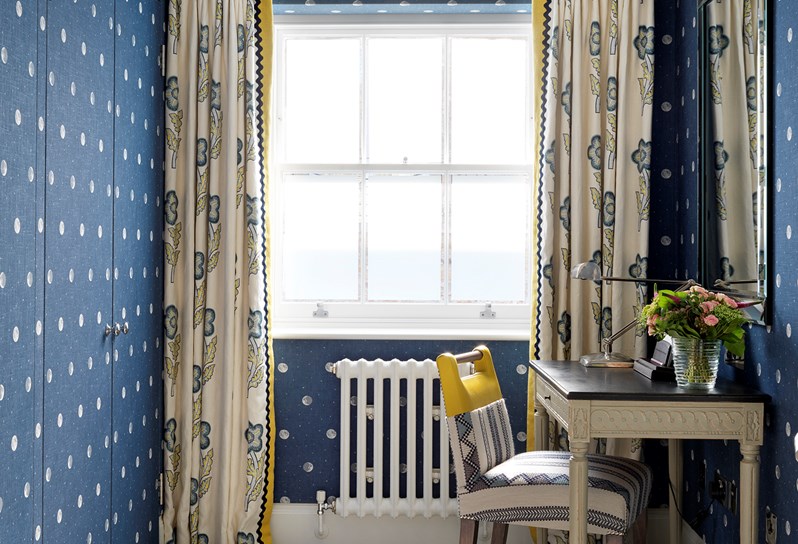 A dressing room dark blue linen walls with a moon pattern and a small writing desk