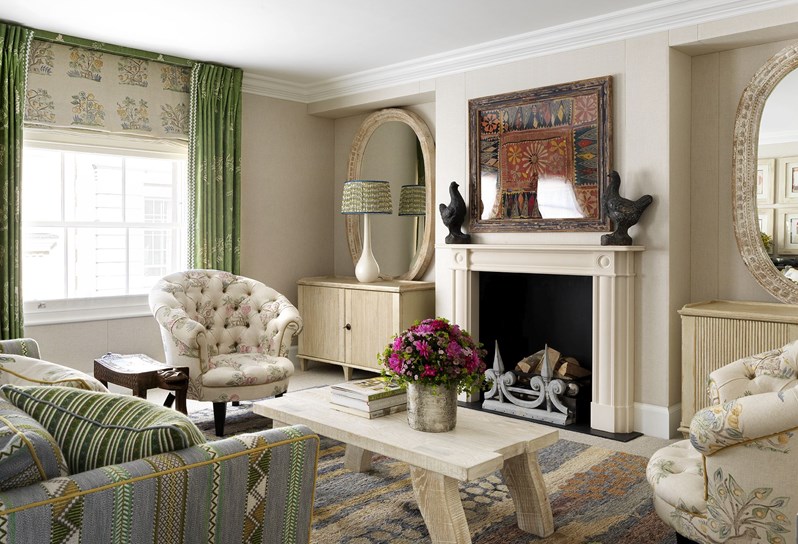 A beautiful drawing room with cream walls and a pale blue and green striped sofa surrounding a wooden coffee table