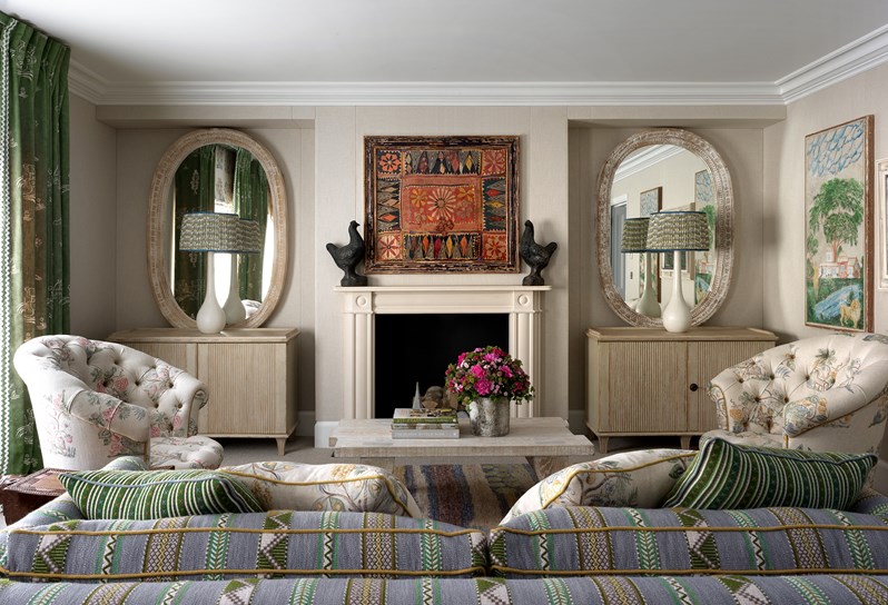 A beautiful drawing room with cream walls and a pale blue and green striped sofa facing towards a fireplace