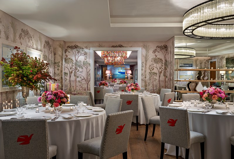 Prince Private event room has walls lined in hand painted mural of trees with beautiful set round banqueting tables and chairs, fresh flowers and spectacular overhead ceiling lights.