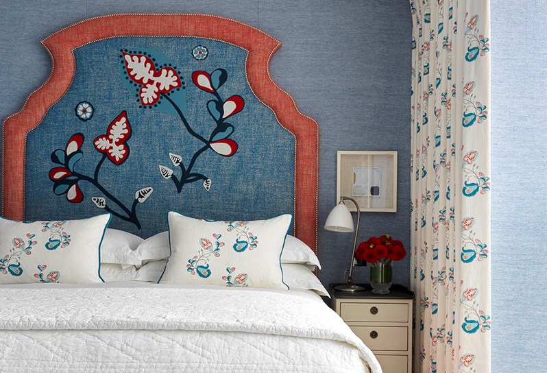 A bedroom with blue fabric walls and a double bed with a blue and red statement headboard