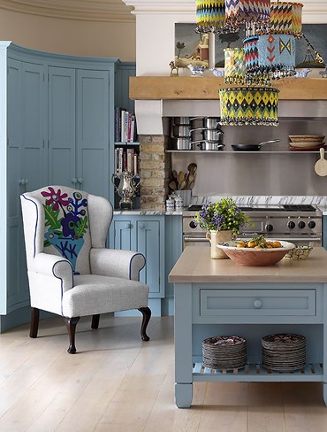 The completely bespoke Couture Wing chair with personalized initials woven into a Matisse inspired applique design. The Couture Wing chair is shown in a kitchen setting. The chair features one of Kit's favorite fabrics, Pierre Frey’s plain linen ‘Arsene’, as a fresh background against a selection of moon wools for the cut outs and piping.