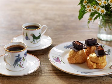 Two Wedgwood Mythical Creatures Espresso cups with saucers, showing a series of characters and patterns that have a primitive, folkloric feel.