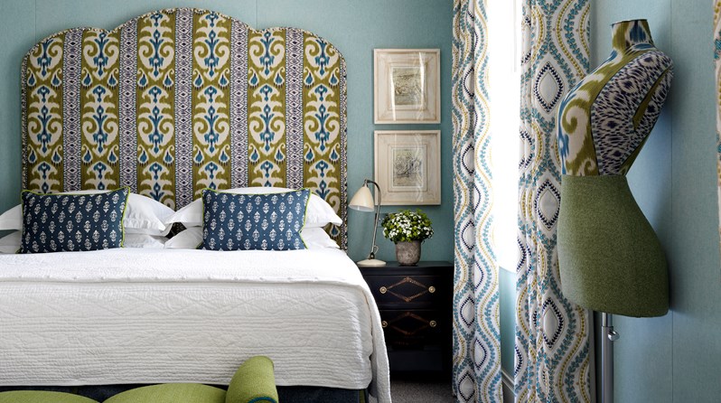 A spacious bedroom with bright blue walls and a king size bed with a blue and green fabric headboard