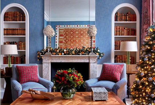 A living area with a fireplace that has Christmas decorations over the mantelpiece and a decorated Christmas tree in the corner of the room.