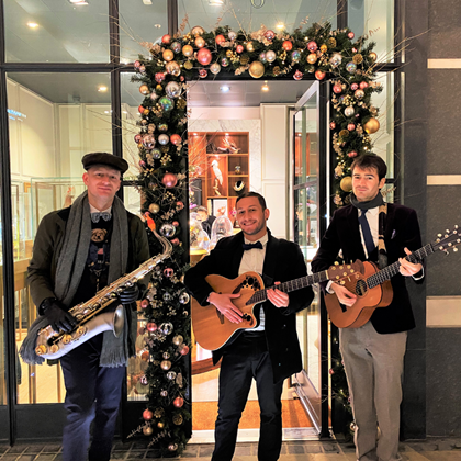 A group of musicians stand outside a shop decorated for Christmas