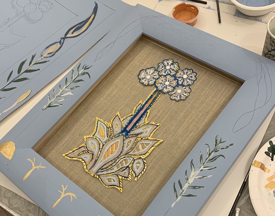 A floral applique artwork in a hand painted frame