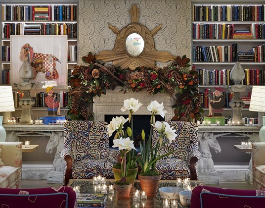 A festive garland hangs over the fireplace in a colourful drawing room.