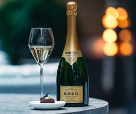 A glass of champagne next to a bottle of Krug with a food pairing.