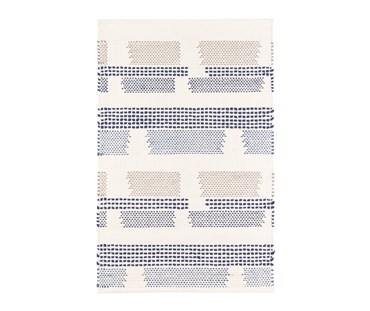 Tonal dotted strips of color on a white ground randomly break at intervals in this witty cotton flatweave rug design