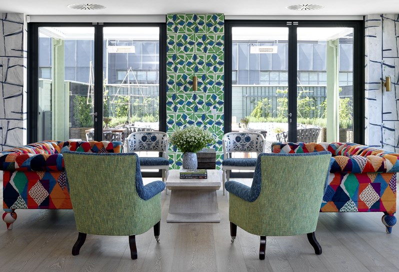 A view of the entertaining area on the top floor at 9-11 Richmond Buildings featuring a lounge seating area and floor-to-ceiling windows and doors with views onto the Roof Terrace.