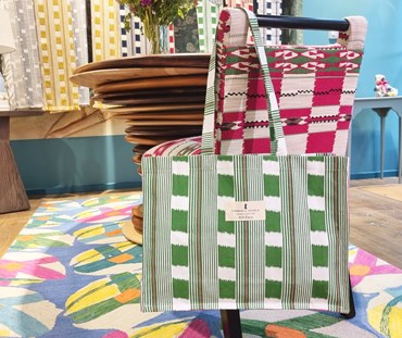 Lost and Found Bag For Life Green is shown hung over a chair.