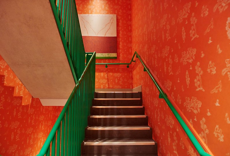 The colourful stairwell at 9-11 Richmond Buildings. The walls have been lined in Kit Kemp's Friendly Folk and the hand rail has been painted in a bright emerald green.