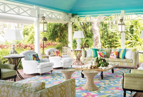 An outdoor living space with a large seating area dressed with colourful rugs and cushions from the Kit Kemp for Annie Selke collection