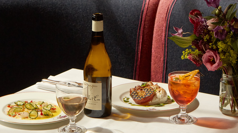 A selection of dishes on a table including raw, marinated scallops, salted cucumber, red chilli, lemon and rosemary as well as buffalo mozzarella, grilled yellow peach, cured pork collar, basil