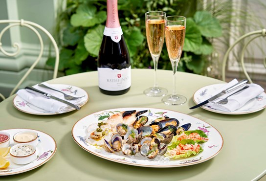 Seafood sharing platter with mussels, cockles, clams, crayfish tails, queen scallops and crab claws is placed on a table alongside Rathfinny English sparkling wine