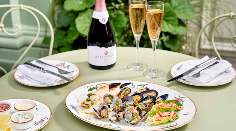 Seafood sharing platter with mussels, cockles, clams, crayfish tails, queen scallops and crab claws is placed on a table alongside Rathfinny English sparkling wine