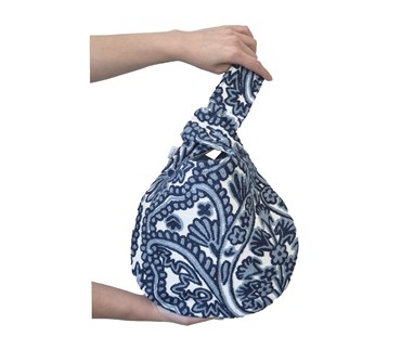 Hands holding loop hole bag with embroidered fabric in shades of blue