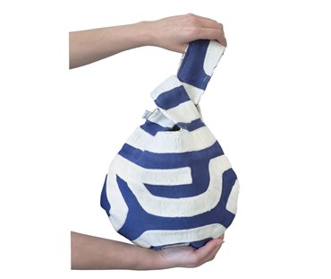 Hands holding swirl loop hole bag, featuring navy background fabric with white embroidery