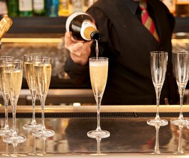 A bartender pours Champagne into several Champagne flutes