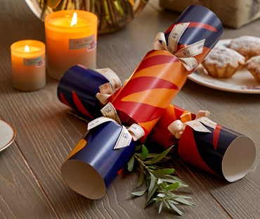 Set of 8 Christmas Crackers, based on Kit's Graphic Rug design, in navy, gold and red with wooden Christmas decoration gift inside