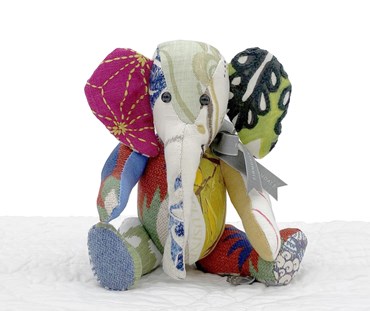 A small patchwork elephant toy made out of re-purposed fabrics, in jewel like tones from Kit Kemps design studio, with one fuchsia, ear one green , with contrasting arms and legs. Each elephant is unique, and varies. This is one of a limited edition of 100, in these colourways.