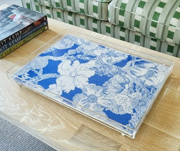 Transparent Acrylic tray, in which is encased a royal blue and natural linen fabric, which is printed with abstract floral pattern, pictured on a coffee table.