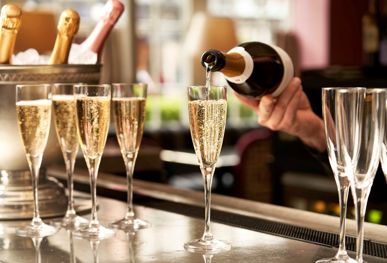 A bartender pours Champagne into a Champagne flute