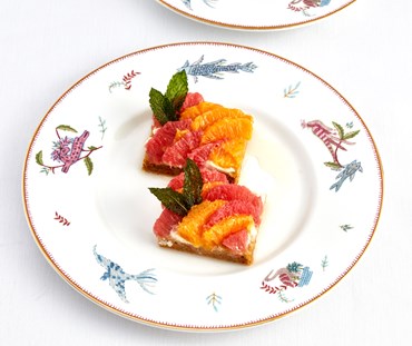 close up shot of mythical creatures afternoon t plate , dressed with slices of grapefruit salad dessert.
