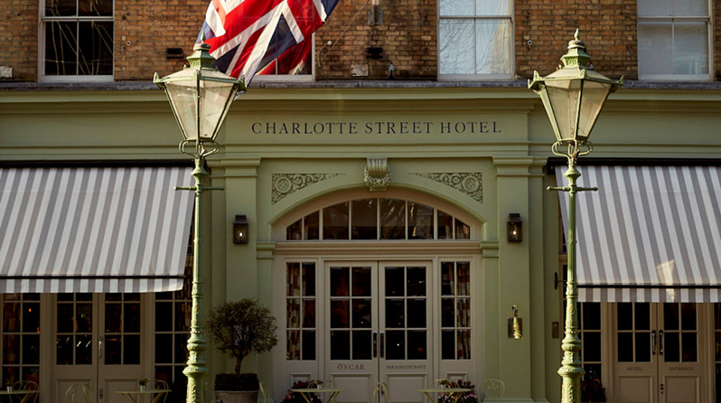 A face on view of the Charlotte Street Hotel exterior showing two olive trees and green lamp posts each side of the entrance doors.