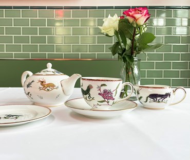 Table setting for tea for one with creamer, showing tea cup and saucer, small tea pot and creamer.
