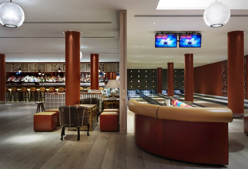The Croc Bowling alley with it's four lanes of bowling spots with bowling balls in colorful balls, with a spacious open plan area with a bar at the back on the left hand side.