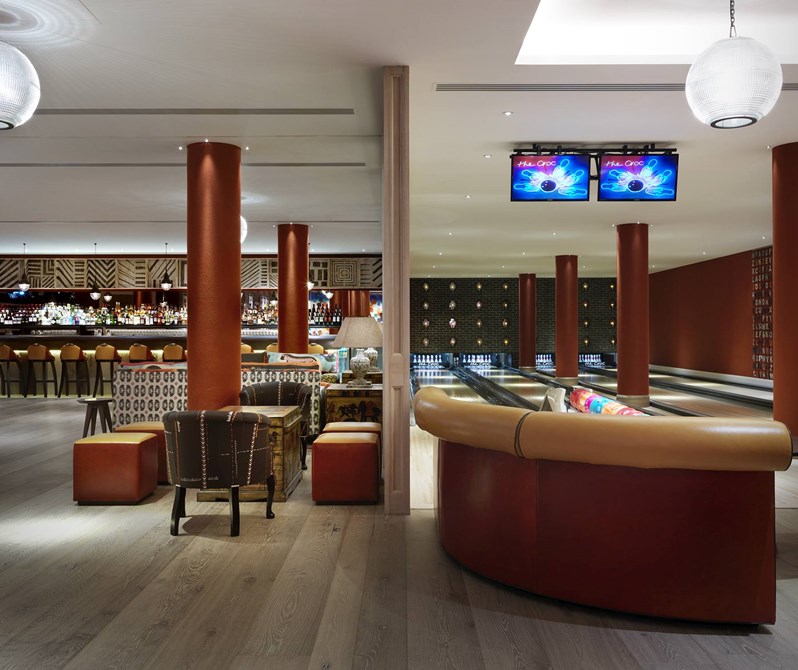The Croc Bowling alley with it's four lanes of bowling spots with bowling balls in colorful balls, with a spacious open plan area with a bar at the back on the left hand side.