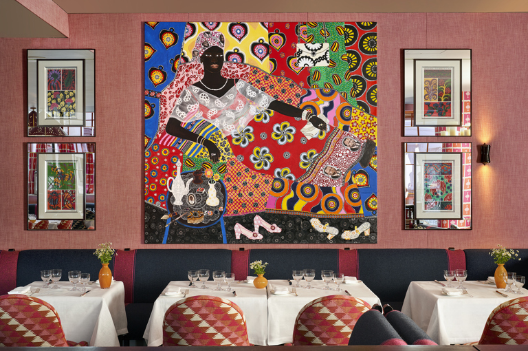 An image of the interior of Brumus Restaurant at Haymarket Hotel, focused on the tables set up for dining and the artwork behind. 