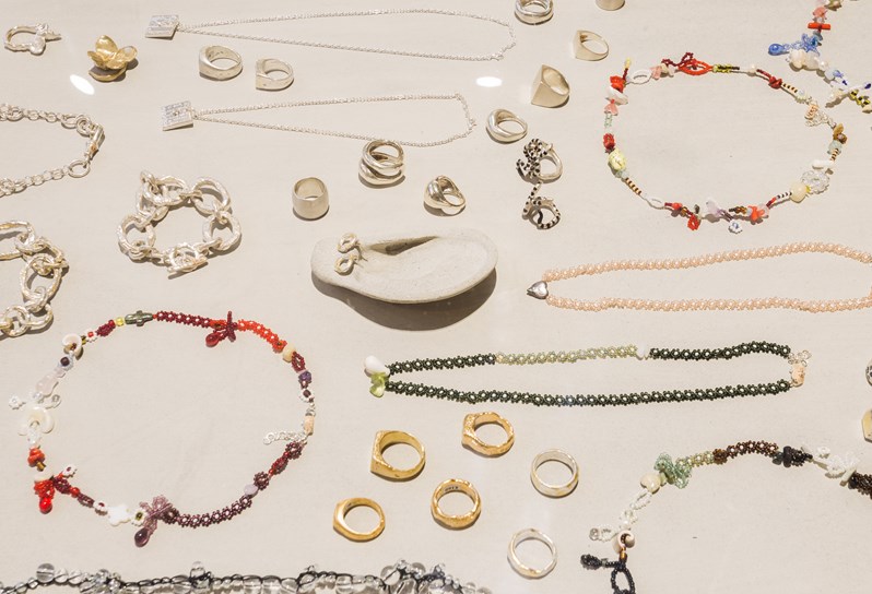 A close up shot of various necklaces, rings, bracelets and earrings all neatly spread out on a beige surface.