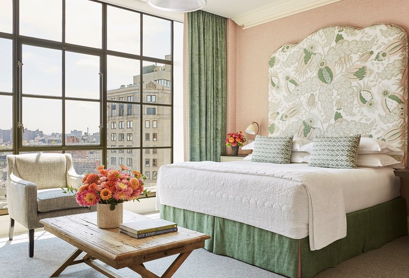 A spacious bedroom in this beautiful junior suite with colourful headboard, high ceilings, floor to ceiling windows and views over SoHo. A beautiful colour scheme with pale pink linen walls and pastel details.