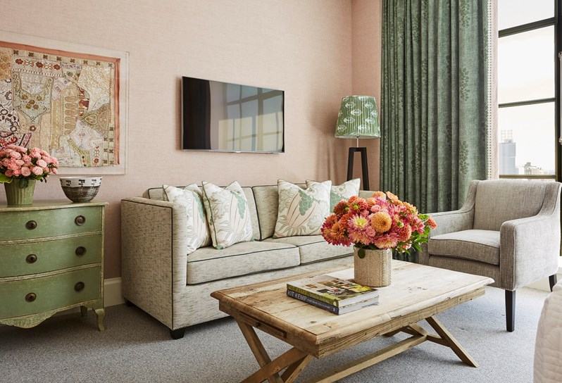 A spacious sitting area with sofa and arm chair in this beautiful junior suite with high ceilings, floor to ceiling windows and views over SoHo. A beautiful colour scheme with pale pink linen walls and pastel details.